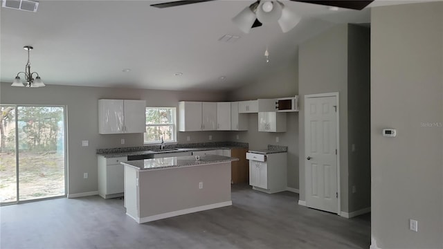 kitchen featuring a center island, hanging light fixtures, ceiling fan with notable chandelier, white cabinets, and sink