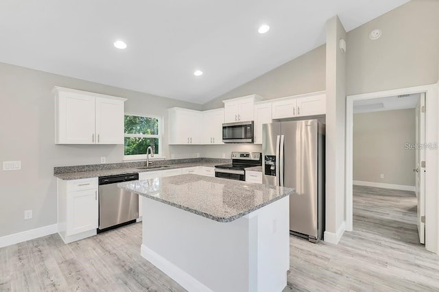 kitchen with white cabinetry, a center island, sink, stainless steel appliances, and light stone counters