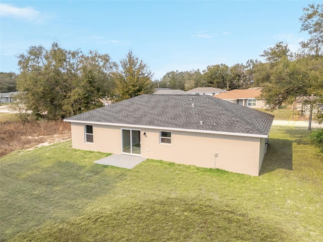 rear view of house featuring a patio area, stucco siding, a lawn, and roof with shingles