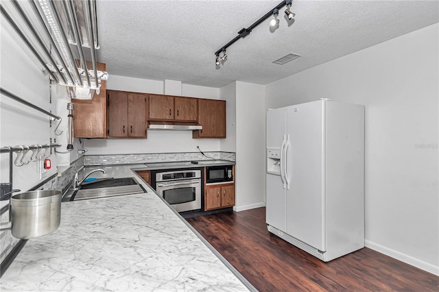5507 SE 107th Pl, Belleview, FL 34420 - kitchen featuring a sink, white refrigerator with ice dispenser, a textured ceiling, stainless steel oven, and under cabinet range hood