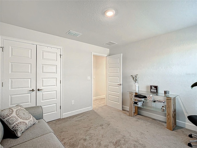 living area featuring light carpet and a textured ceiling