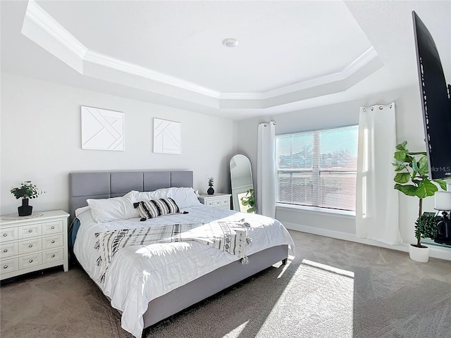 carpeted bedroom with a tray ceiling and ornamental molding