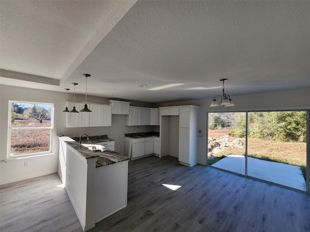 kitchen featuring hardwood / wood-style floors, white cabinets, dark stone counters, and sink