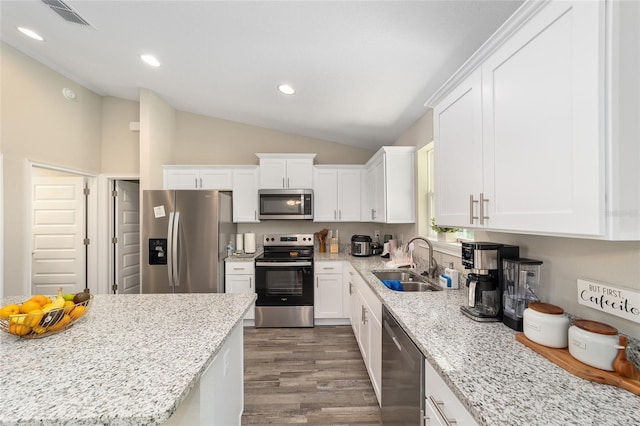 kitchen with appliances with stainless steel finishes, light stone counters, white cabinetry, and sink