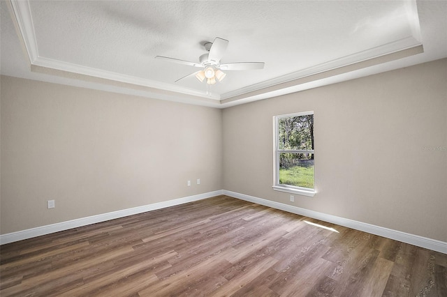 unfurnished room with ceiling fan, a raised ceiling, dark hardwood / wood-style flooring, a textured ceiling, and ornamental molding