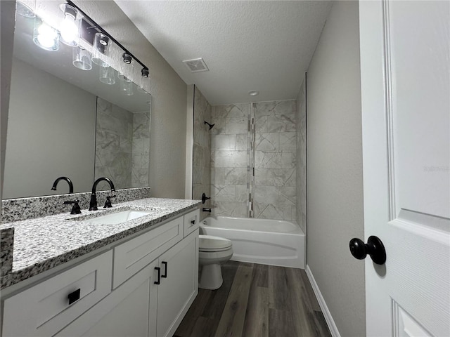 full bathroom featuring vanity, a textured ceiling, wood-type flooring, toilet, and tiled shower / bath