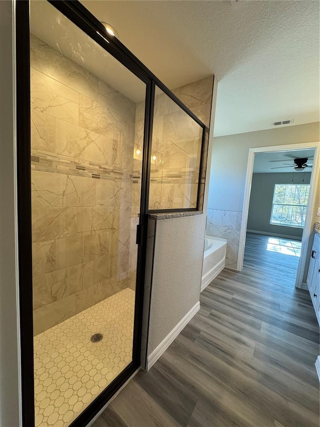 bathroom featuring hardwood / wood-style flooring, ceiling fan, and independent shower and bath