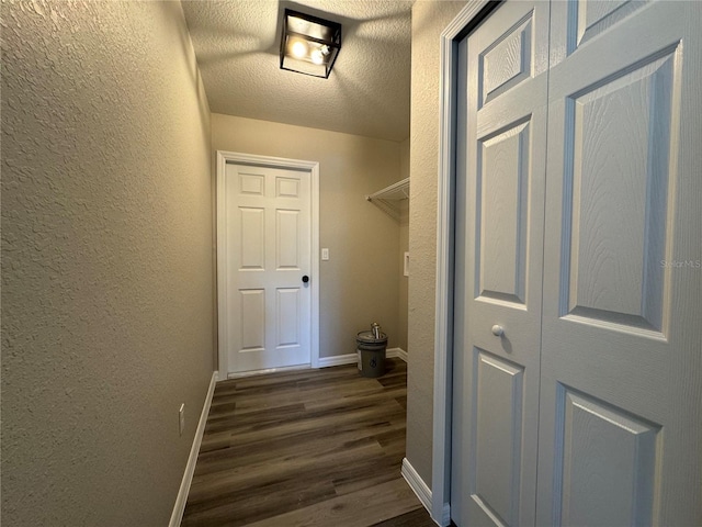 clothes washing area featuring a textured ceiling and dark wood-type flooring