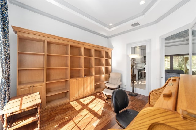 living area with hardwood / wood-style flooring, a raised ceiling, and ornamental molding