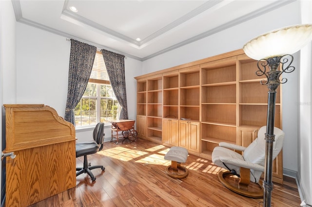 office with a raised ceiling, wood-type flooring, and ornamental molding