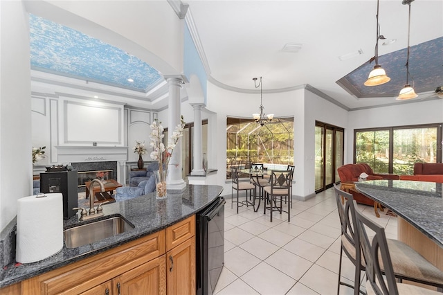 kitchen with a high end fireplace, a raised ceiling, sink, ornamental molding, and ornate columns