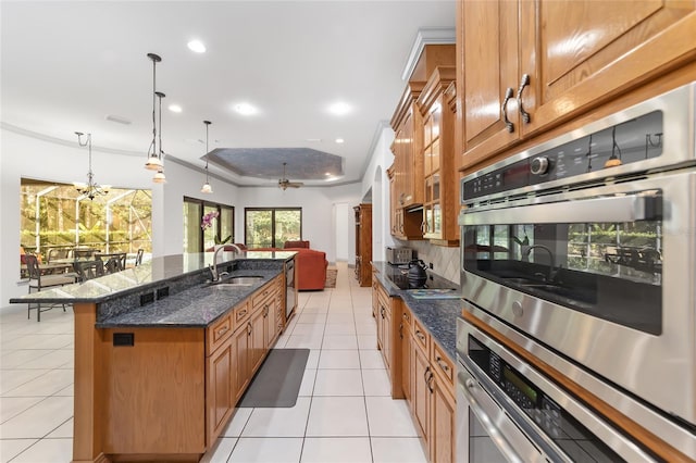 kitchen featuring ornamental molding, a breakfast bar, sink, hanging light fixtures, and an island with sink