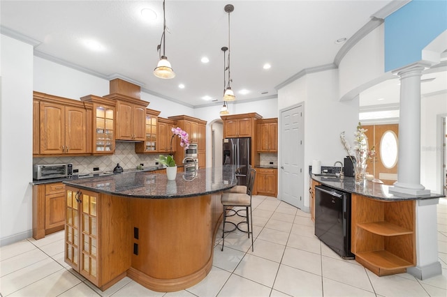 kitchen with kitchen peninsula, decorative columns, tasteful backsplash, light tile patterned floors, and a kitchen island