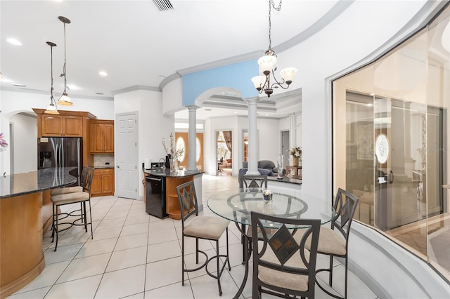 dining room with ornate columns, sink, a chandelier, light tile patterned floors, and ornamental molding