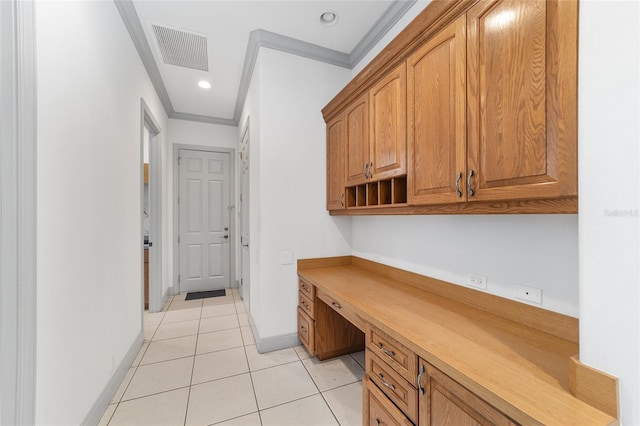 office area with light tile patterned floors, built in desk, and ornamental molding