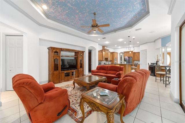 tiled living room featuring a raised ceiling, ceiling fan, and crown molding