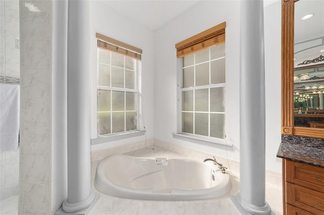 bathroom with vanity, tiled bath, and decorative columns