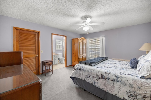 carpeted bedroom featuring a textured ceiling, ceiling fan, and ensuite bathroom