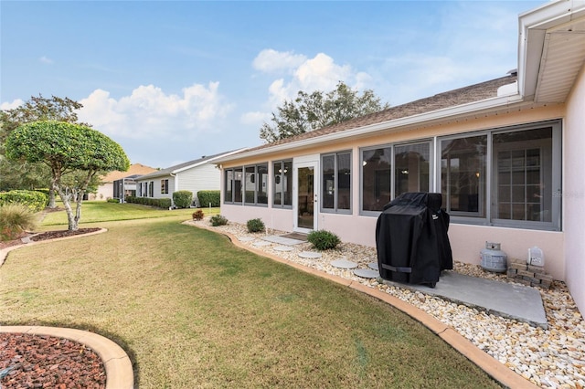 rear view of house featuring a sunroom and a yard