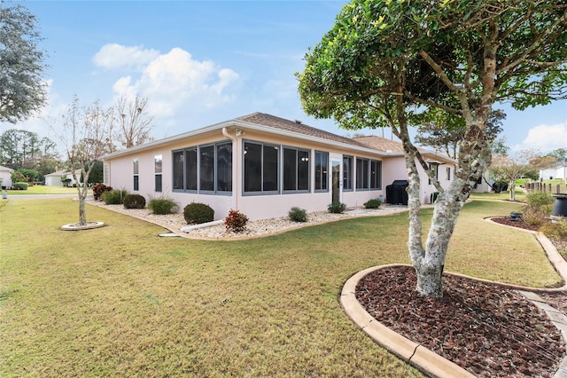 rear view of house featuring a lawn and a sunroom