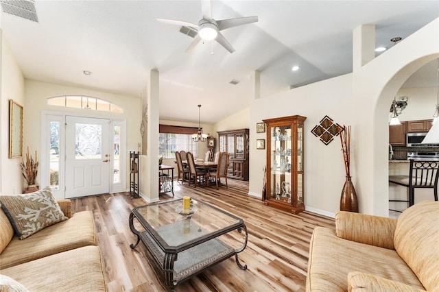 living room featuring high vaulted ceiling, light hardwood / wood-style floors, and ceiling fan with notable chandelier