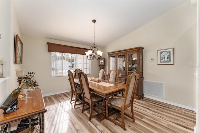 dining area with a chandelier, light hardwood / wood-style flooring, and vaulted ceiling