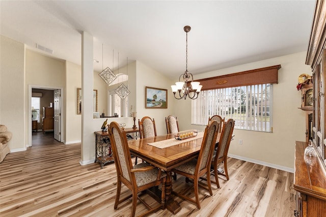 dining area with a chandelier, vaulted ceiling, and light hardwood / wood-style flooring