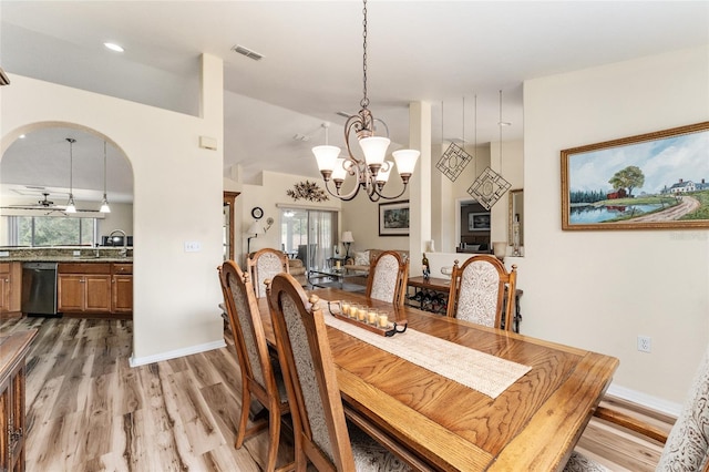 dining room featuring sink, wood-type flooring, and ceiling fan with notable chandelier