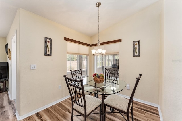 dining area featuring light wood-type flooring, an inviting chandelier, and lofted ceiling