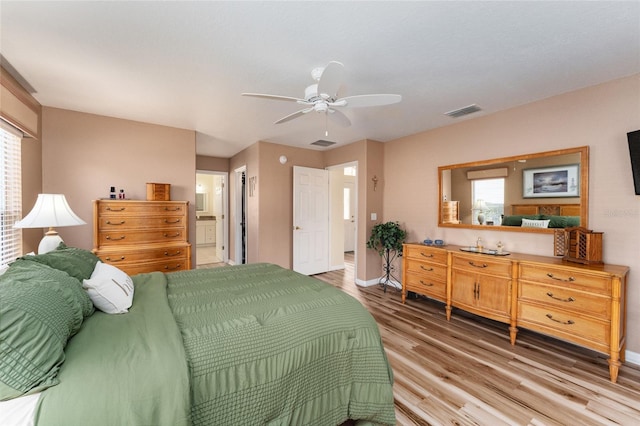 bedroom with multiple windows, wood-type flooring, ensuite bathroom, and ceiling fan