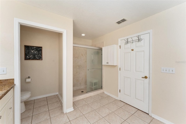 bathroom featuring tile patterned floors, vanity, toilet, and a shower with shower door