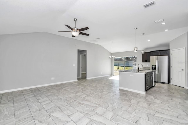 kitchen featuring sink, stainless steel fridge, lofted ceiling, a center island with sink, and ceiling fan with notable chandelier