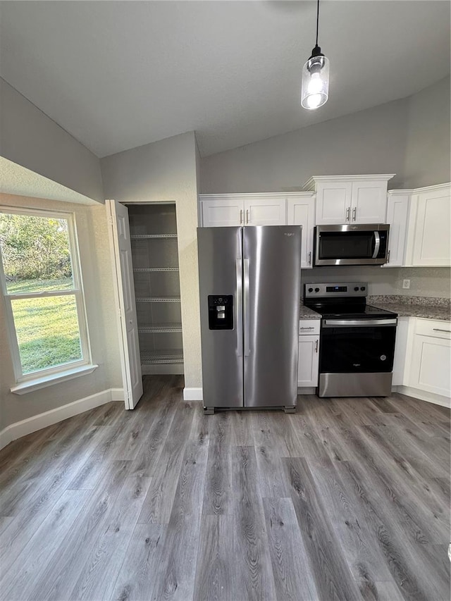 kitchen with white cabinetry, decorative light fixtures, vaulted ceiling, appliances with stainless steel finishes, and light wood-type flooring