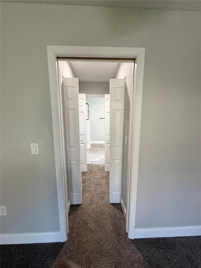 hallway with dark colored carpet