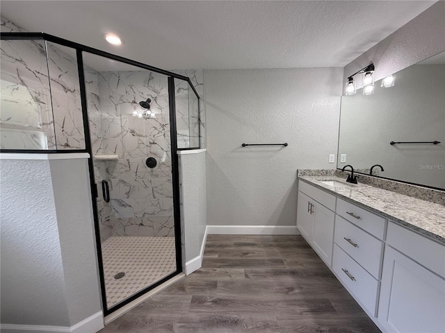 bathroom with hardwood / wood-style floors, vanity, walk in shower, and a textured ceiling