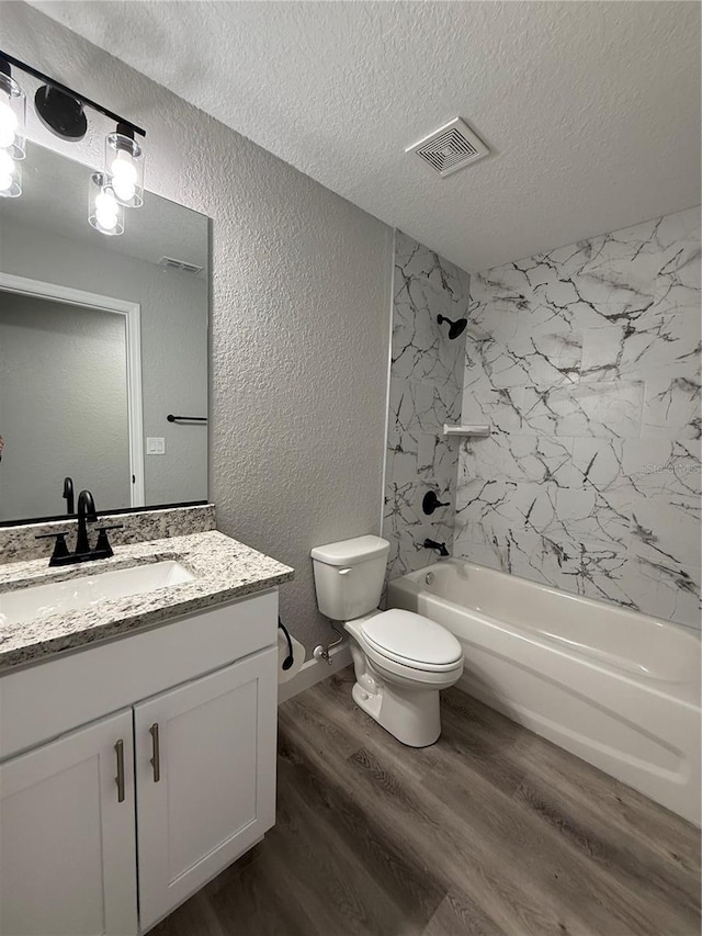 full bathroom featuring tiled shower / bath combo, hardwood / wood-style floors, a textured ceiling, toilet, and vanity