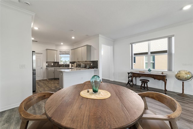 dining space featuring ornamental molding, dark wood-type flooring, and sink