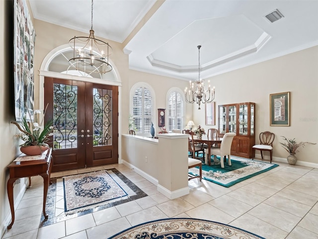 tiled entrance foyer with french doors, a tray ceiling, crown molding, and a notable chandelier