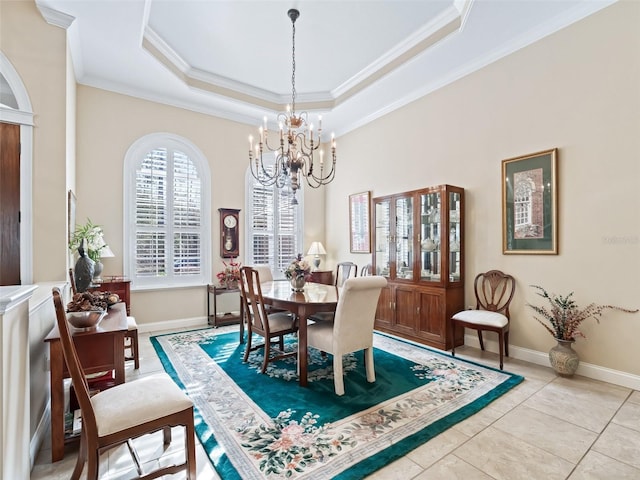 tiled dining space with a raised ceiling, ornamental molding, and a notable chandelier