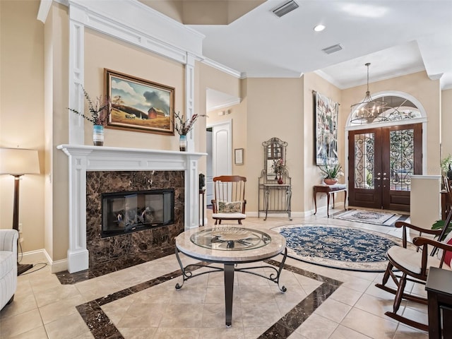 entrance foyer with a fireplace, french doors, a chandelier, and ornamental molding