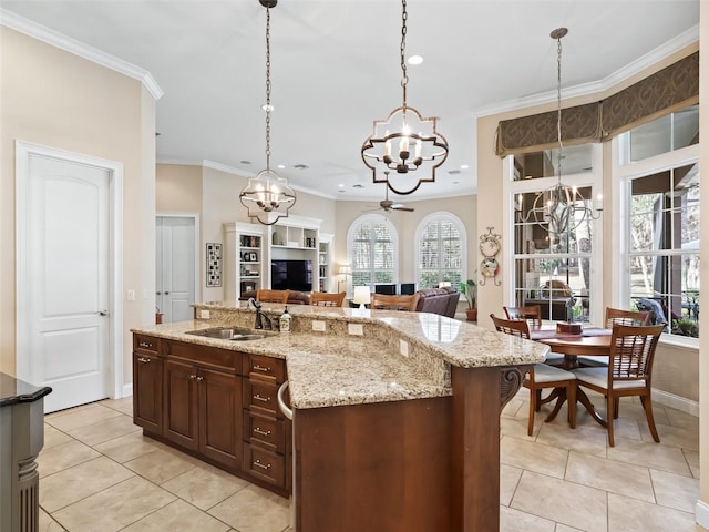 kitchen featuring sink, an island with sink, pendant lighting, and light tile patterned floors