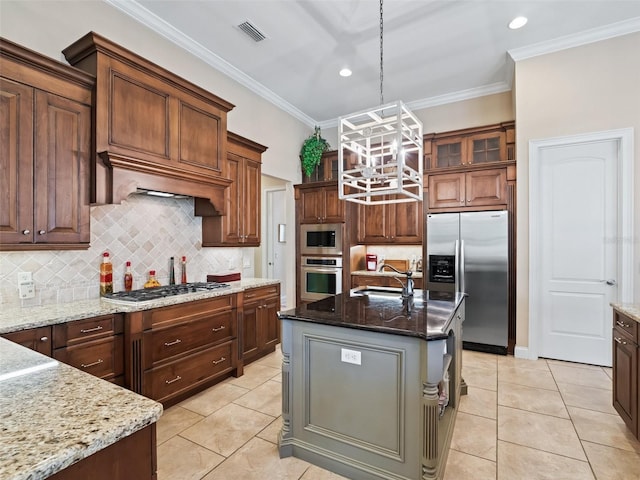 kitchen featuring dark stone counters, a kitchen island with sink, hanging light fixtures, and stainless steel appliances