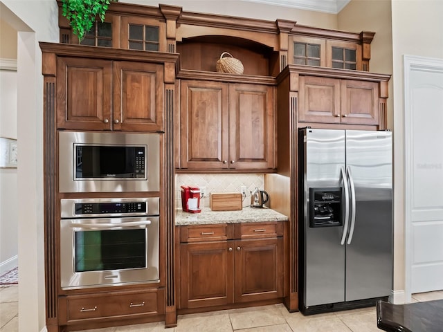 kitchen featuring light stone countertops, stainless steel appliances, backsplash, light tile patterned floors, and ornamental molding