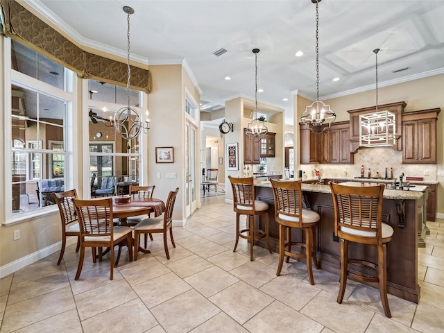 kitchen featuring light stone countertops, a breakfast bar, crown molding, pendant lighting, and an inviting chandelier