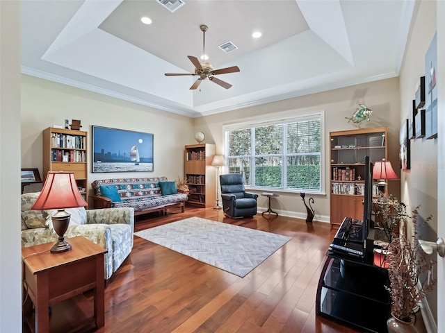 living room featuring a tray ceiling, crown molding, ceiling fan, and hardwood / wood-style flooring