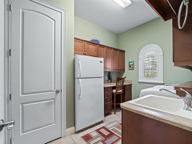 kitchen with white fridge, light tile patterned flooring, and sink