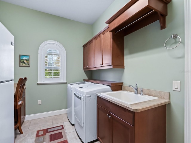 laundry area featuring washing machine and clothes dryer, light tile patterned floors, cabinets, and sink