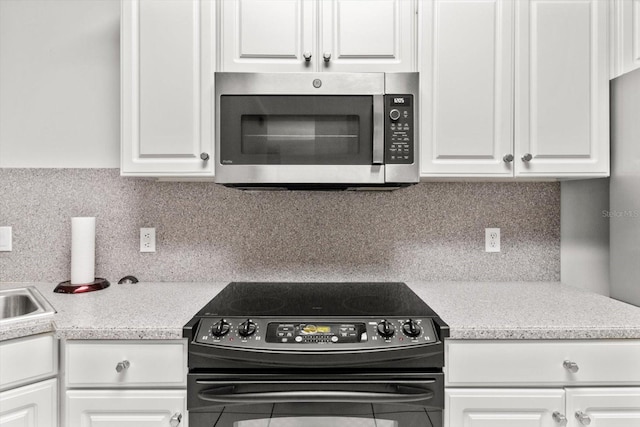 kitchen featuring white cabinetry, black range with electric cooktop, and tasteful backsplash