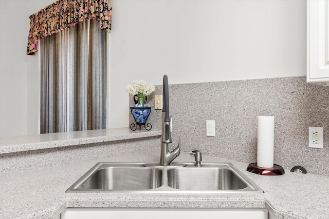 kitchen with white cabinets, decorative backsplash, and sink