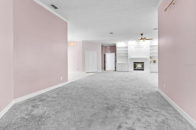 unfurnished living room featuring crown molding, a large fireplace, light carpet, and ceiling fan with notable chandelier